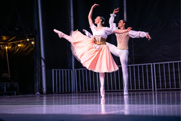 Members of First State Ballet perform on stage in white tutus and small crowns.